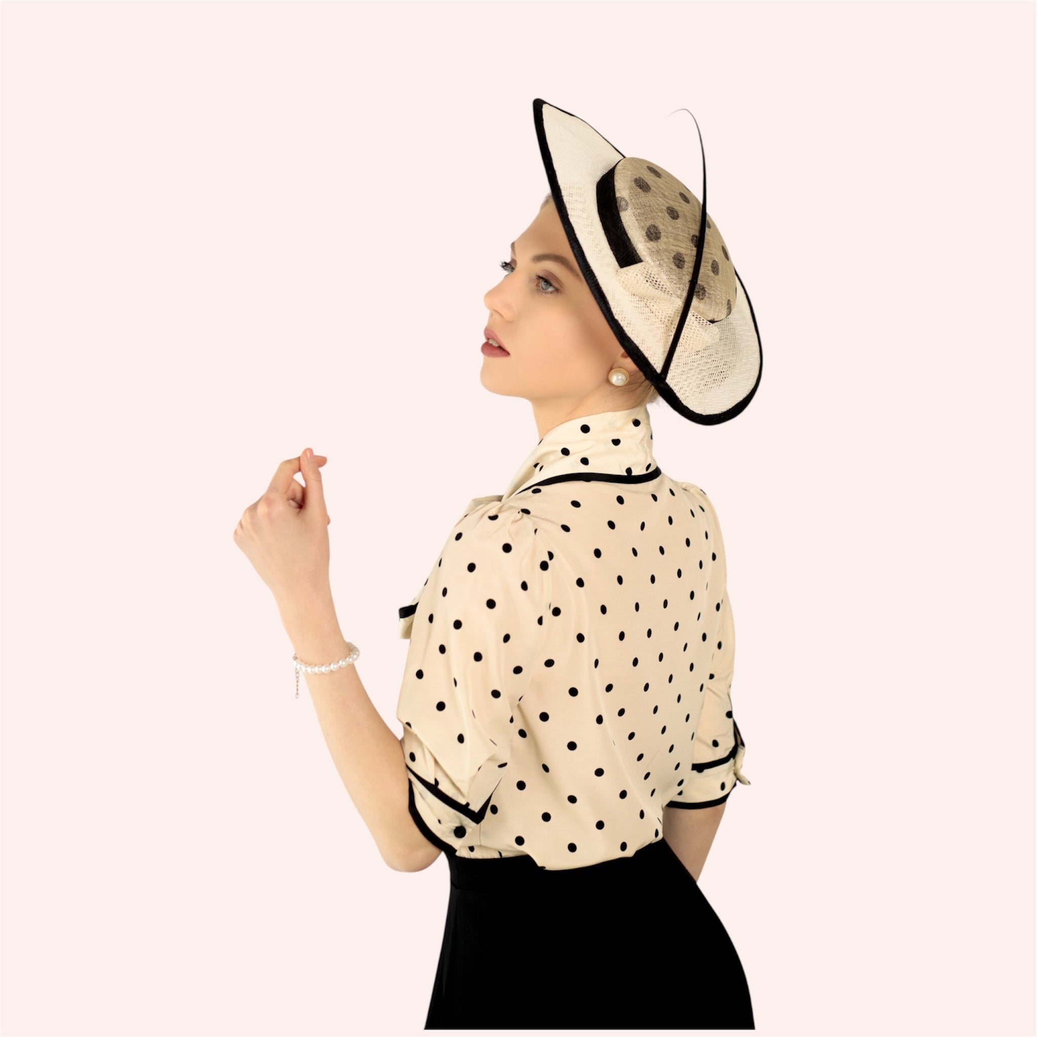Woman wearing a polka dot blouse and a decorative hat on a white background